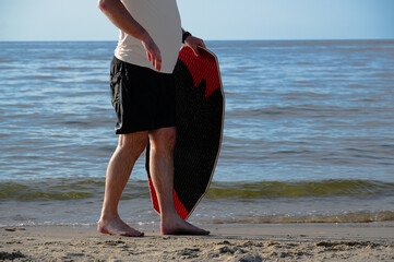 Man with surfboard standing on the beach, close-up.