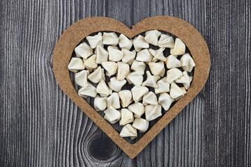 handmade manti (turkish ravioli type dumplings) on wooden heart shape bowl, before cooking