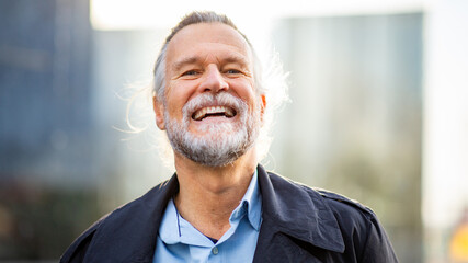 Close-up of joyful older man laughing with city buildings in background
