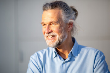 Fototapeta premium Elderly man looking away with gentle smile in sunlight
