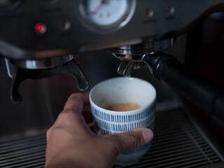 Hand Holding Cup of Freshly Brewed Coffee from Espresso Machine