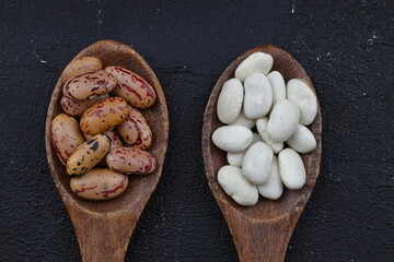 red kidney beans in wooden spoon isolated on dark background.