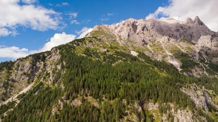 Fototapeta premium Majestic Mountain Valley with Lush Forests and Rugged Peaks Under a Cloudy Sky
