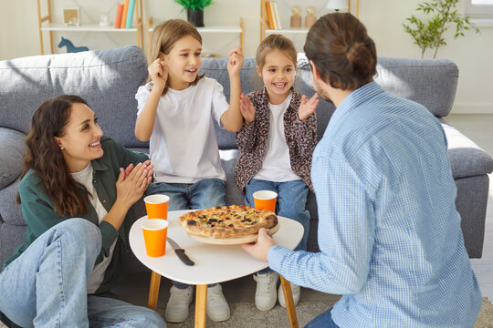 Happy father, mother, daughter and son eating delicious homemade pizza for lunch, gathering together and having good mood, enjoying weekend time. Happy moments and family time concept
