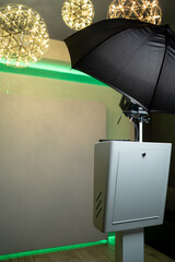 Photo booth setup with black umbrella light and backdrop.