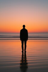 Silhouette of male adult watching ocean sunset on beach