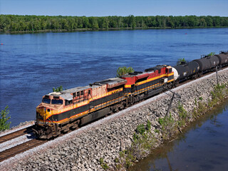 Aerial view of a railroad locomotive pulling a freight train of cars along the backwaters of the Mississippi river