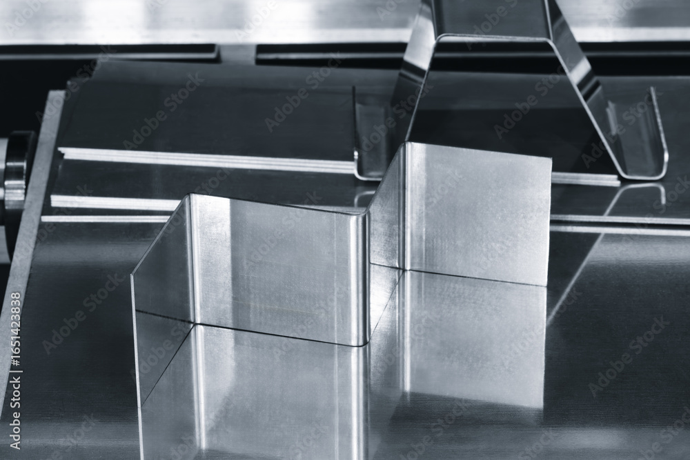 Poster metal pieces are being cut by machine. pieces all same size and shape, and they are arranged in a ro