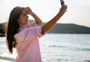 Beautiful woman taking selfie pictures on the sunset beach