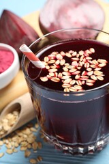 Superfood. Tasty juice with oats in glass and beetroots on light blue wooden table, closeup
