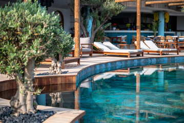 Empty deck chairs around outdoor luxury swimming pool 