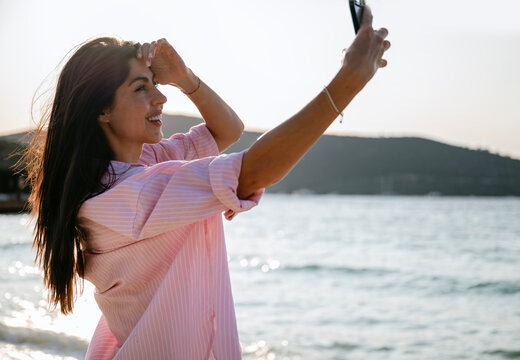 Beautiful woman taking selfie pictures on the sunset beach - Powered by Adobe