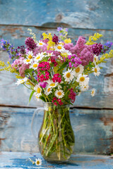 Beautiful bouquet of summer wild flowers on wooden blue background