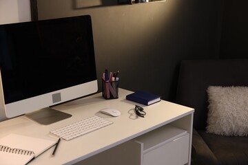 Desk with computer, stationery and glasses at home office, closeup. Interior design