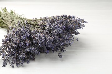Bunch of aromatic lavender flowers on white wooden table, closeup. Space for text