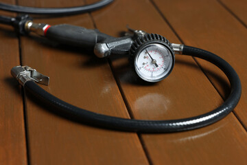 One tire inflation gun with gauge on wooden background, closeup