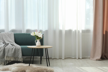 Stylish furniture near window with curtains in living room. Interior design