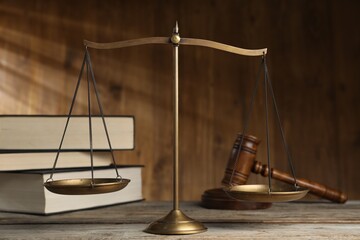 Scales of justice, gavel and books on wooden table, selective focus