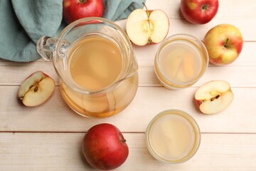 Tasty compot in glasses, jug and fresh apples on wooden table, flat lay
