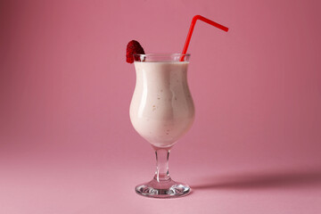 Tasty raspberry milkshake in glass on pink background
