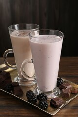 Different tasty milkshakes in glasses and ingredients on wooden table, closeup