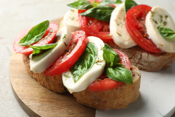 Delicious sandwiches with mozzarella cheese, tomatoes and basil on light grey table, closeup