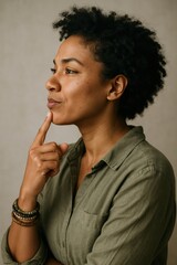 Thoughtful african adult woman in green shirt reflecting with curly hair and bracelet
