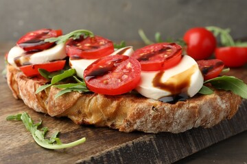 Delicious sandwich with mozzarella cheese, balsamic sauce, tomatoes and arugula on table, closeup