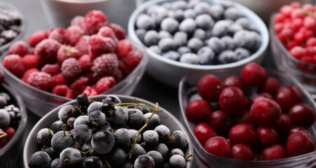Different ripe frozen berries in bowls on table, closeup