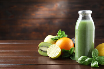 Tasty juice in glass bottle, fresh fruits, mint and basil on wooden table. Space for text