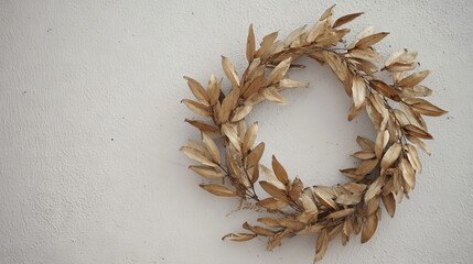 Fototapeta premium Decorative wreath made of dried leaves, elegantly arranged in a circular shape, hanging on a textured white wall, adding a touch of natural beauty to the interior decor