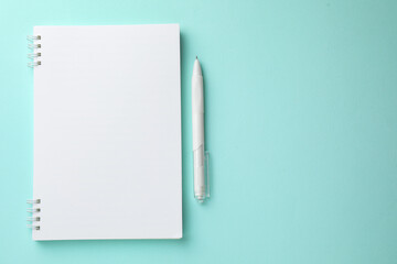 White notebook and pen on light blue background, flat lay. Space for text