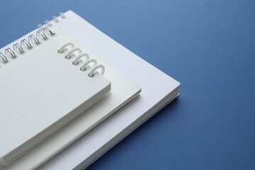 Three white notebooks on blue background, closeup