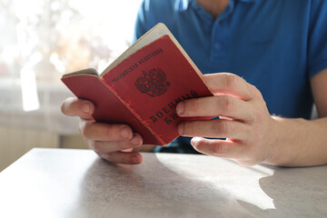 In the hands of a young Caucasian man, a document of military service.