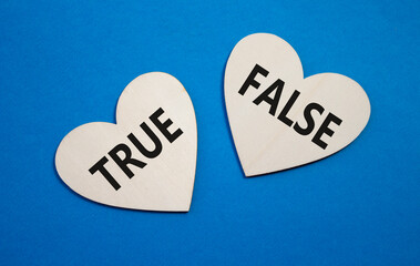 True or False symbol. Concept word True or False on wooden hearts. Beautiful blue background....