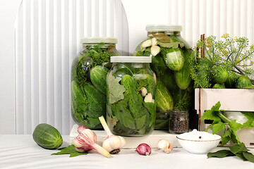 Pickled cucumbers in jars with garlic and dill on wooden kitchen table, rustic style,Homemade...