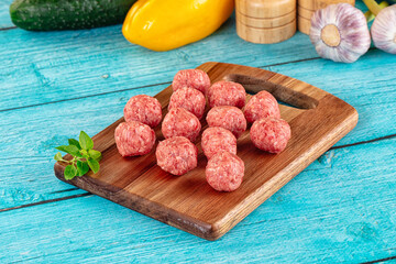 Raw beef meatballs over board