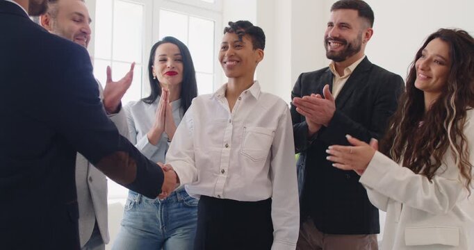 Handshake between boss and happy best female employee in recognition of work achievements, celebrate good results on meeting. Congratulations and applause from colleagues standing together in office