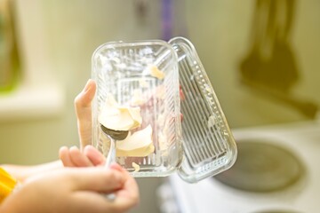 metal spoon scooping a piece of butter from a rectangular glass butter dish, close-up of creamy dairy product