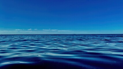deep blue ocean water surface with gentle ripples under clear sky horizon ideal for background...