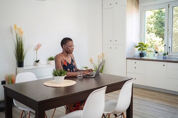 Focused Young Woman Working From Home on Laptop at Dining Table