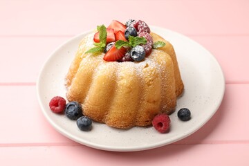 Delicious bundt cake with powdered sugar, berries and mint on pink wooden table, closeup