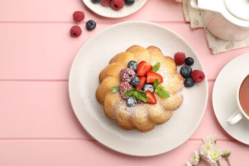 Delicious bundt cake with powdered sugar, berries and mint on pink wooden table, flat lay
