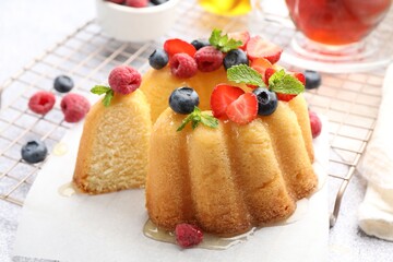 Tasty Bundt cake with berries, honey and mint on table, closeup