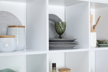 Shelving unit with different dishware, glass and other kitchen utensils indoors