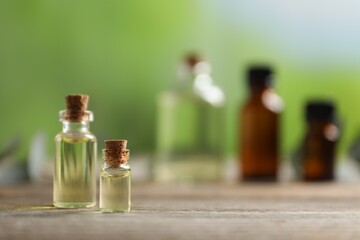 Bottles of essential oils on wooden table outdoors, closeup. Space for text