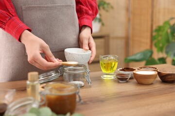 Making natural scrub. Woman adding sugar into jar at wooden table, closeup