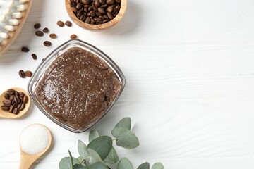Natural body scrub in glass bowl, ingredients and brush on white wooden table, flat lay. Space for...