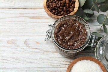 Natural body scrub in glass jar and ingredients on wooden table, above view. Space for text