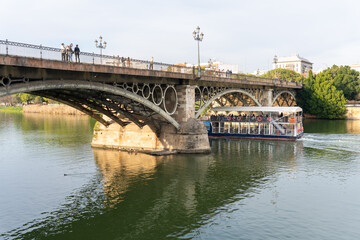 Bridge and Boat: A scenic view showcases an elegant bridge over tranquil water. Beneath it, a tourist boat cruises, while a few people stroll along the bridge, and architectural detail.